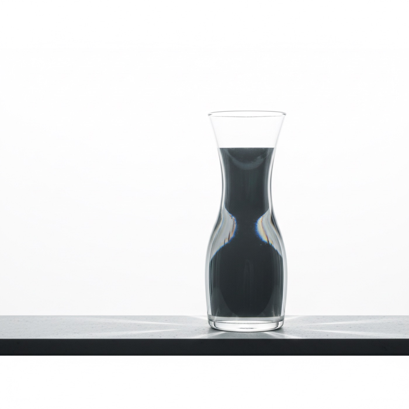 A hand-blown carafe and two tumblers on a pale table, morning light through the glass